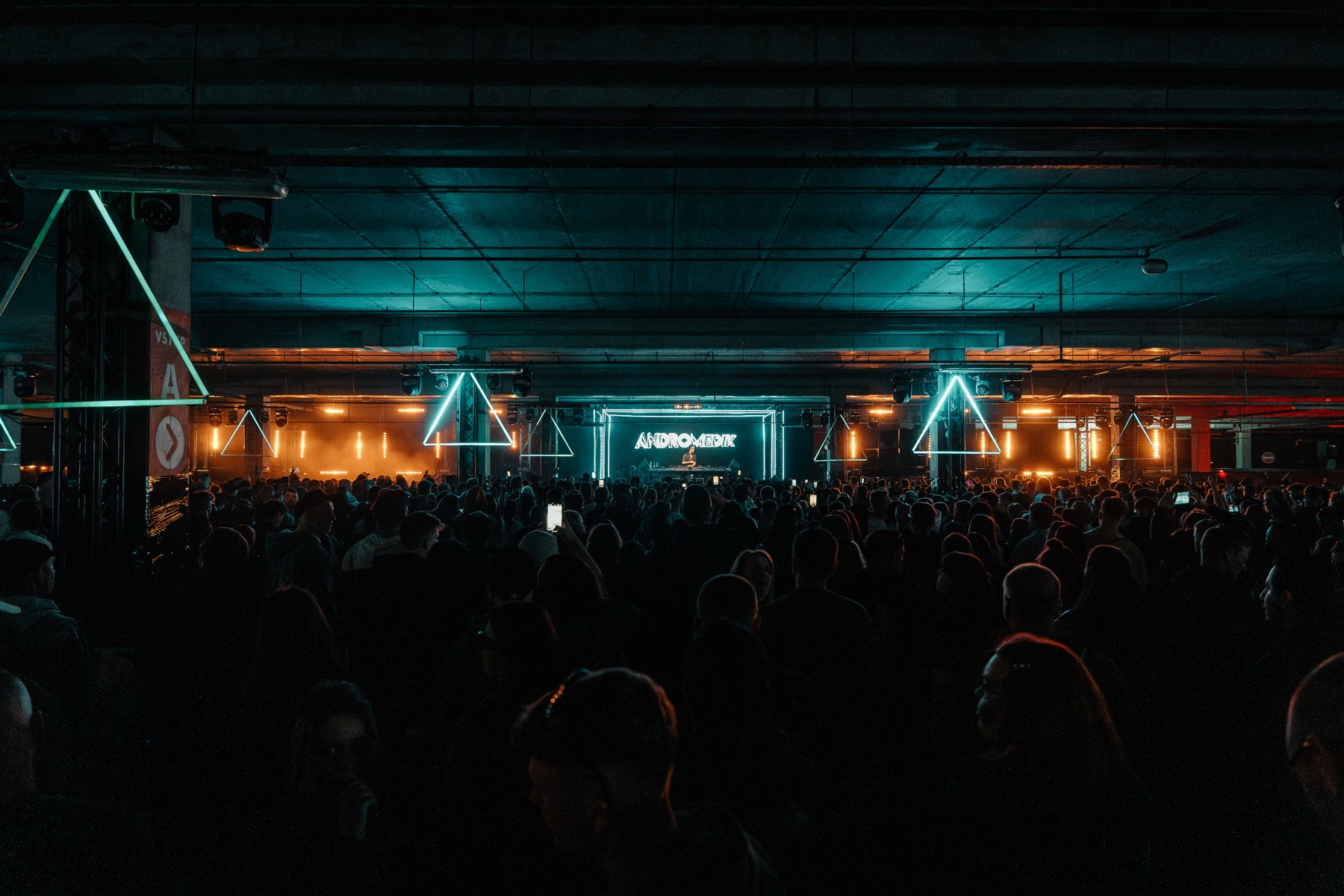 BASSIZM — crowd in an industrial venue with orange and turquoise lights